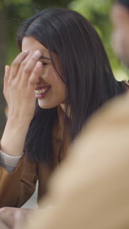 Vertical-Video-Close-Up-Of-Muslim-Couple-On-Date-Meeting-And-Talking-At-Table-On-City-Street-Together-1